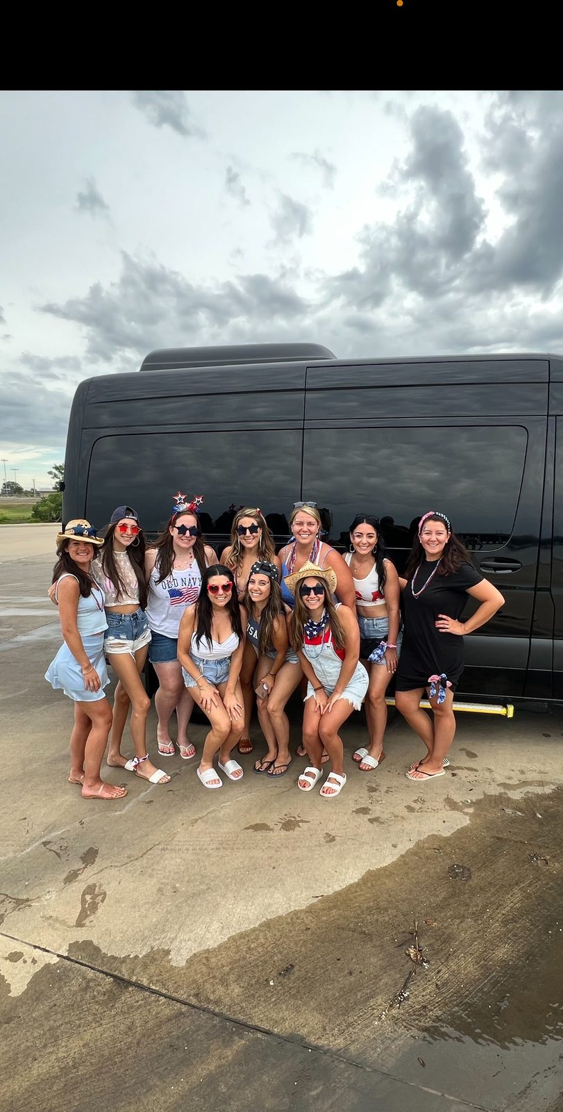 Group of friends in patriotic outfits posing in front of a black Sprinter